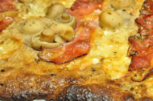 Grov pizza af koldthævet dej med parmesanost og parmaskinke