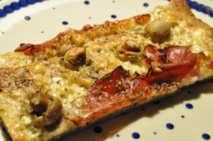 Grov pizza af koldthævet dej med parmesanost og parmaskinke