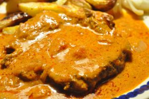 Steaks i flødesauce med tomat, løg og hvidløg